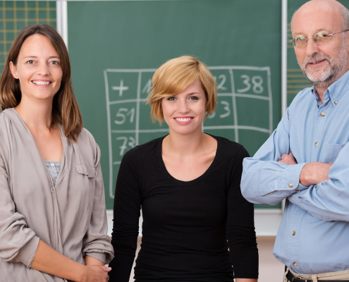 Lehrerkolleg*innen vor der Tafel im Klassenraum