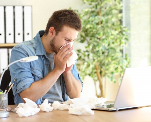 Krank zur Arbeit | Mann mit Taschentüchern vor dem Labtop