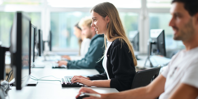 Studierende im PC-Raum mit Blick auf die Computer.