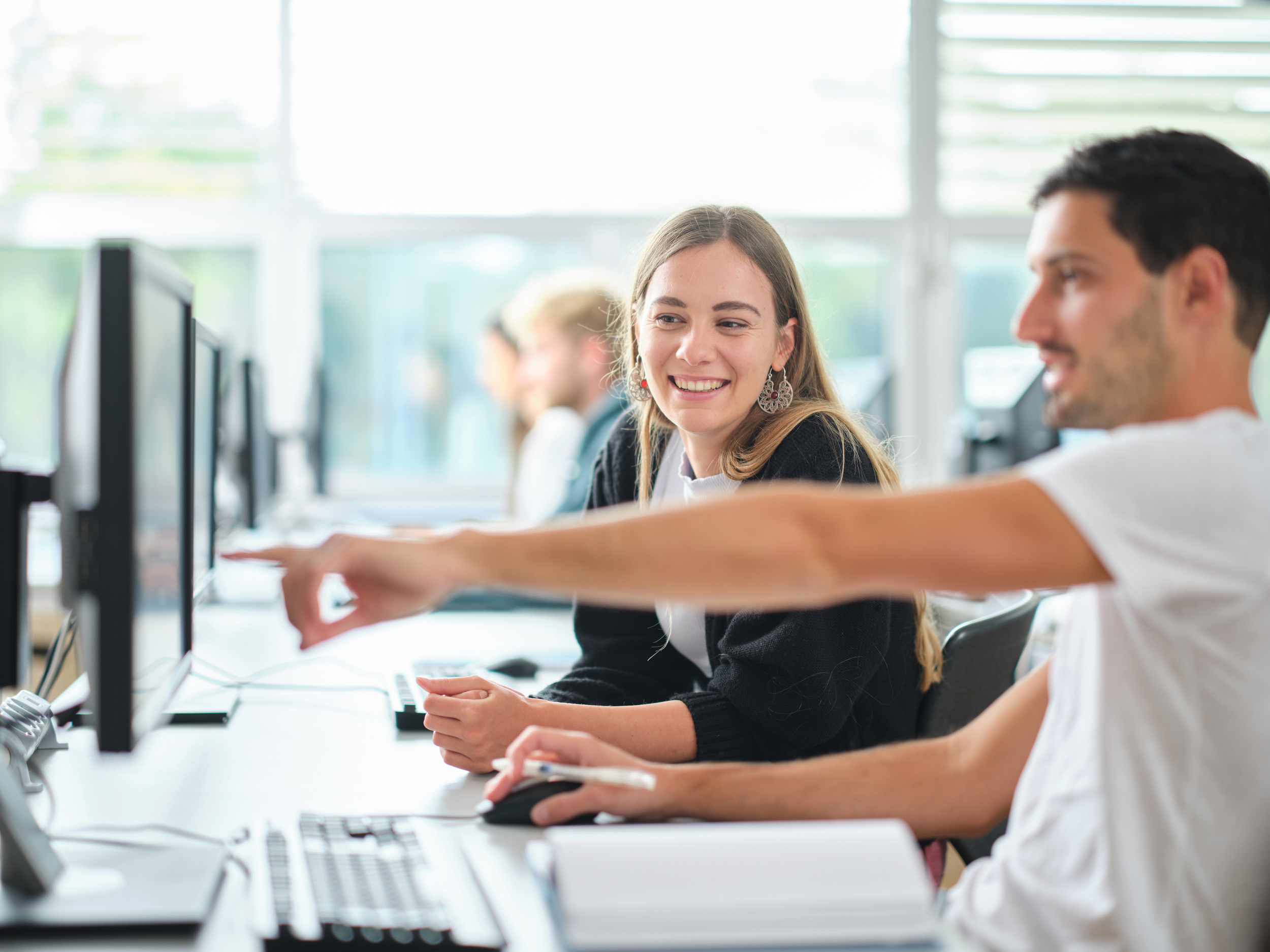 Studierende im PC-Raum. Student zeigt einer Studentin etwas am Bildschrim.